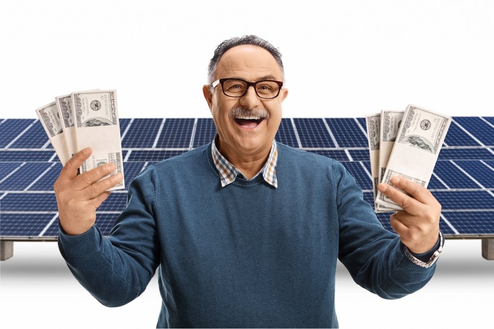 an old man with money infront of solar panels