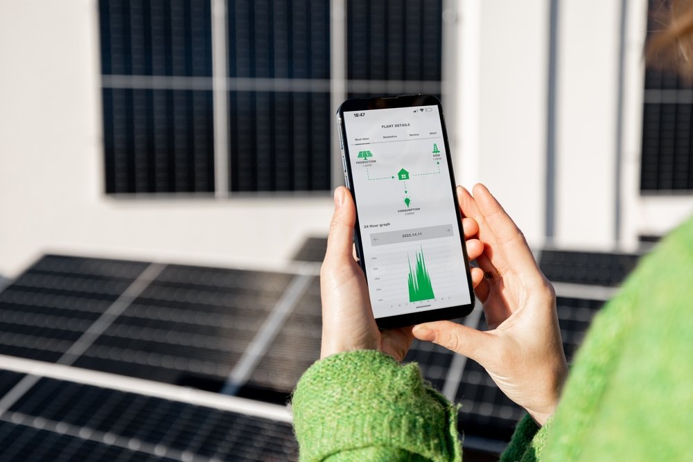 woman checking power production of solar panels on her phone